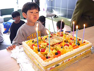 巨大なフルーツケーキのロウソクを吹き消す